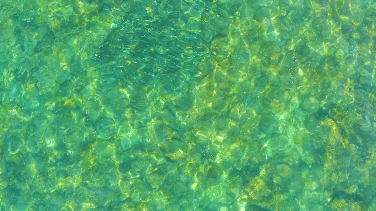 Turquoise water surface with bright rippled light patterns.