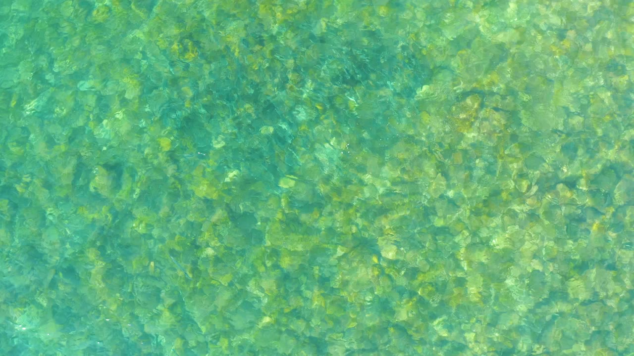 Clear green-blue water at El Tule Beach Los Cabos shows the rocky seabed through fine surface ripples, with no visible people.