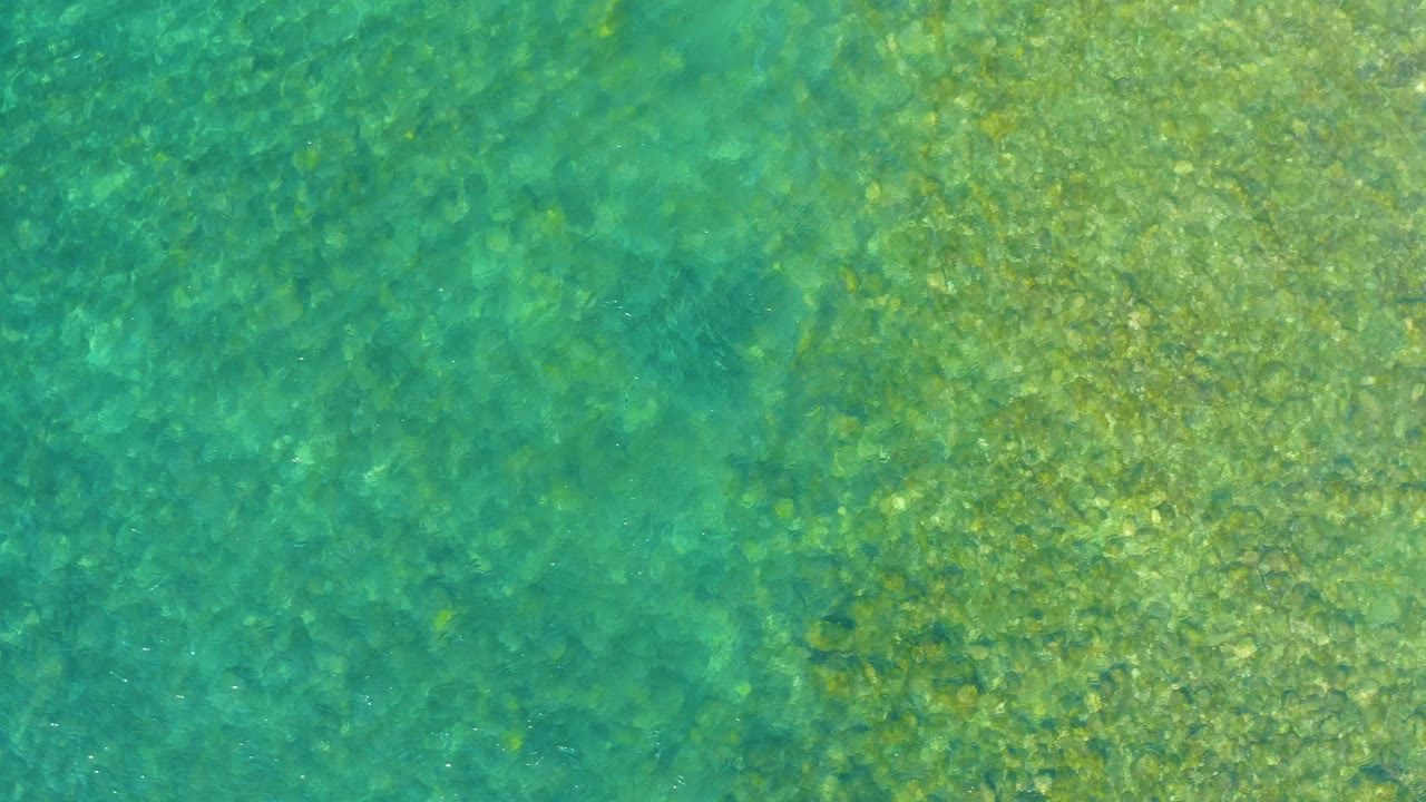 Turquoise and green shallow water over a rocky bottom.