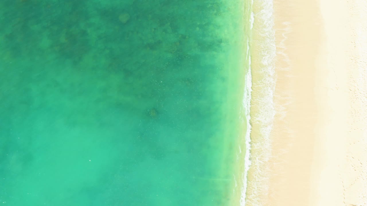Overhead turquoise water meeting pale sandy beach