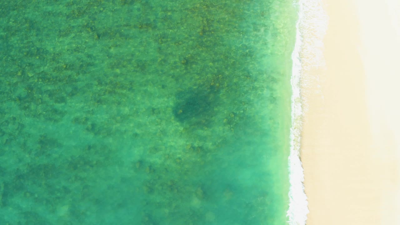 White surf line separates shallow water and sand.