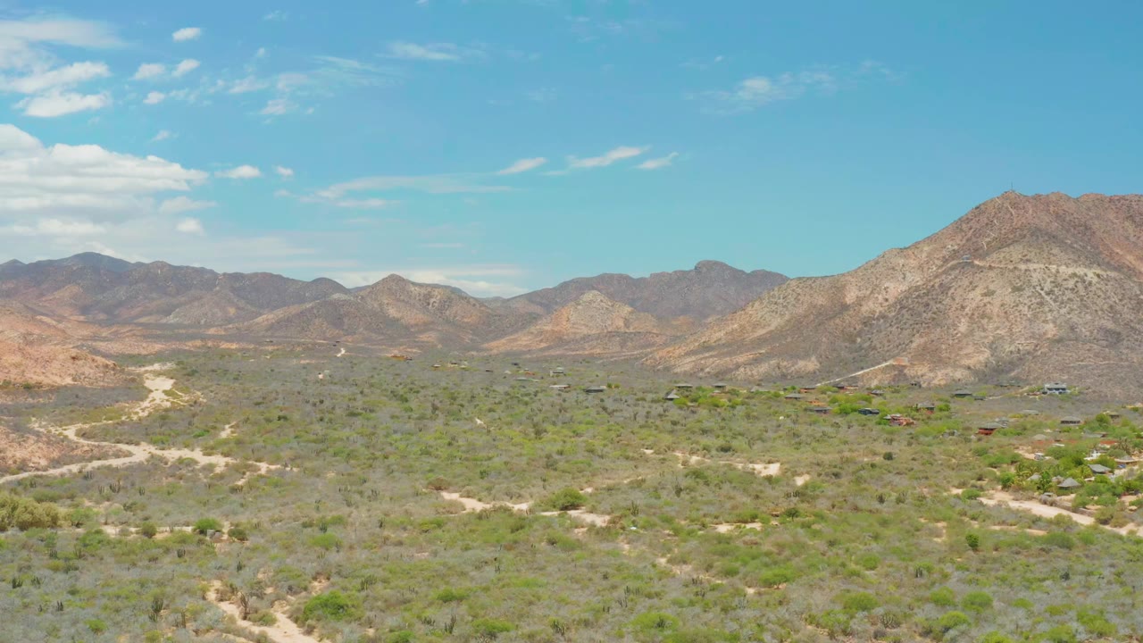 Wide desert valley with pale road curves and mountain backdrop
