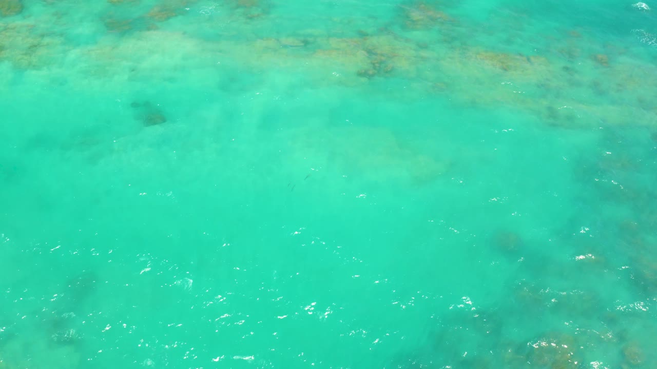 Clear Cabo Pulmo water shows darker submerged seabed areas beneath soft surface ripples, with no visible people or boats.