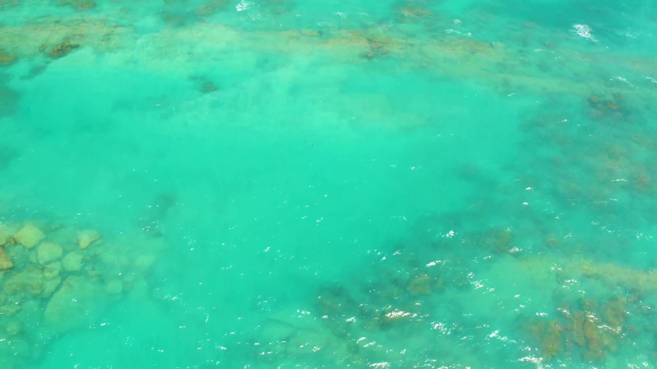Shallow turquoise water with rocks visible at the left edge.