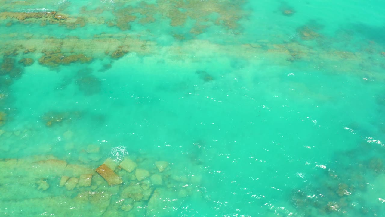 Clear turquoise water ripples across pale underwater rocks in Cabo Pulmo, Baja California Sur, with small white surface bubbles and no visible people.