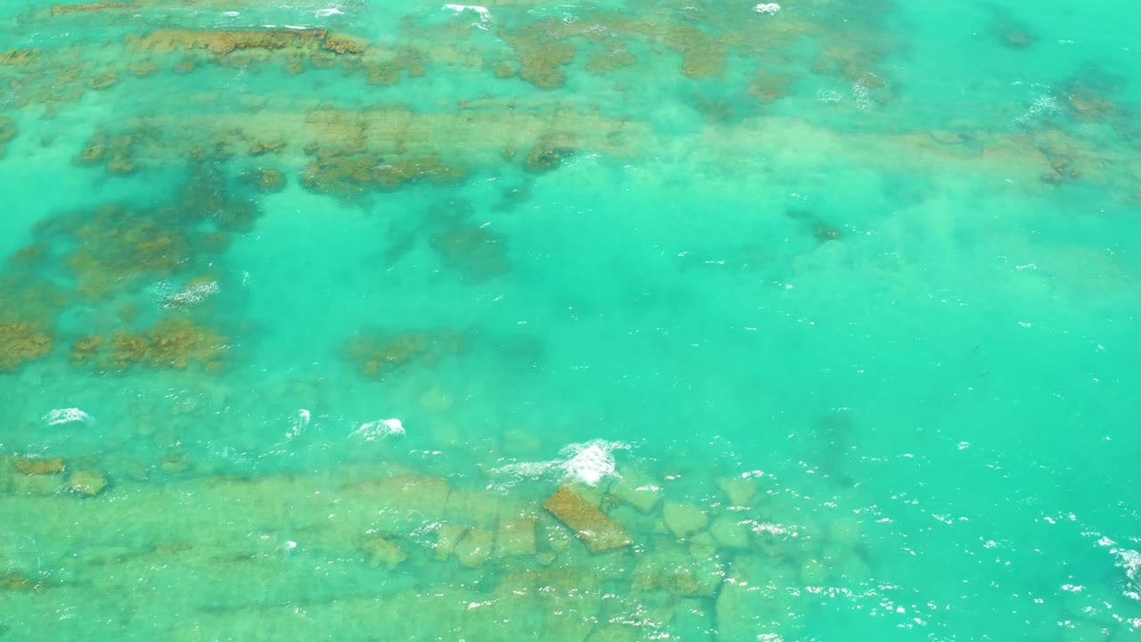 Cabo Pulmo shallow sea fills the frame with a horizontal band of submerged rocks through the middle and small white ripple marks, with no visible people.