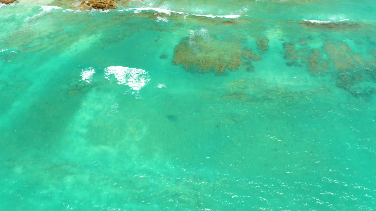 At 0:00, Cabo Pulmo turquoise water fills the frame from above, with shallow reef patches visible below the surface and no visible people.
