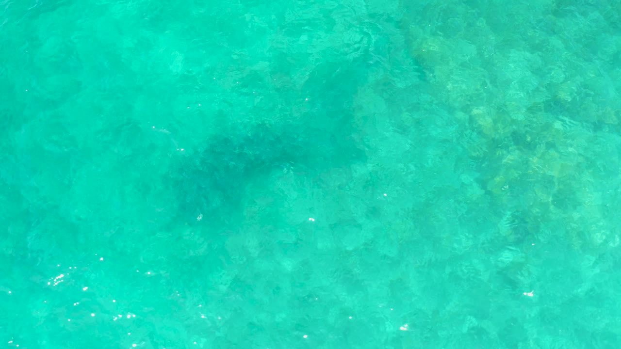 Turquoise shallow water at El Tule Beach Los Cabos fills the frame, with soft underwater shadows, broken sun reflections, and no visible people or shore objects.