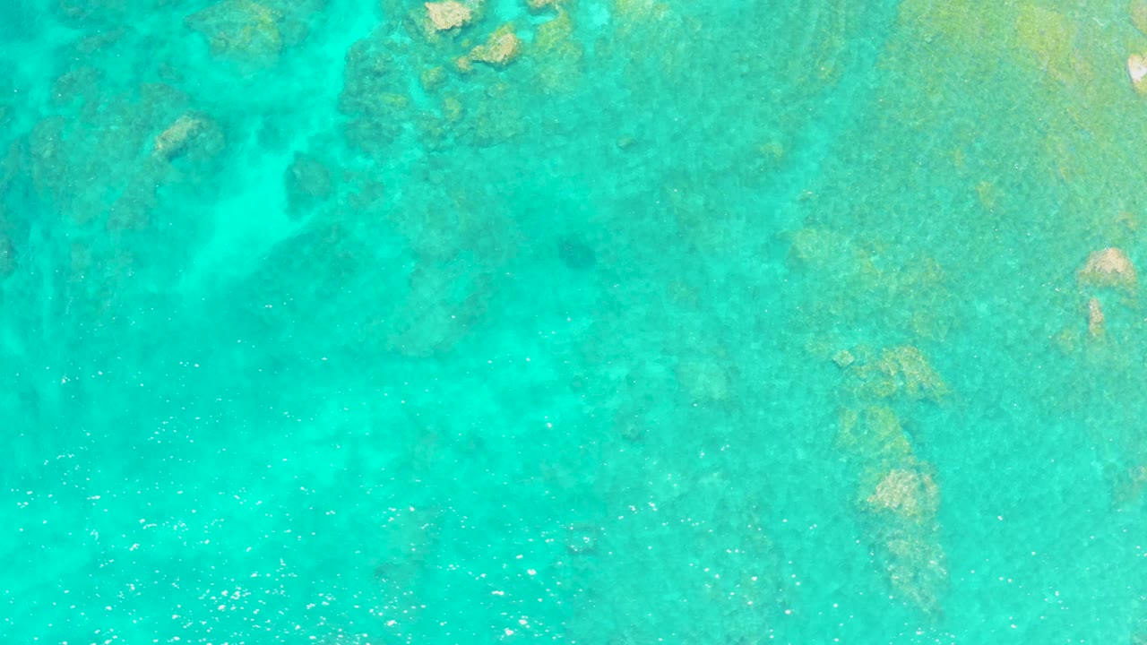 Overhead turquoise shallow ocean with visible rocks beneath the water.