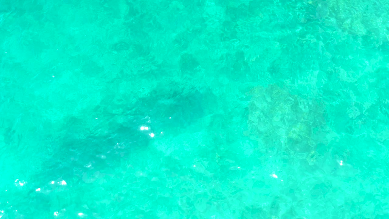 Clear turquoise water at El Tule Beach Los Cabos with mottled seabed texture below the surface and no visible people.