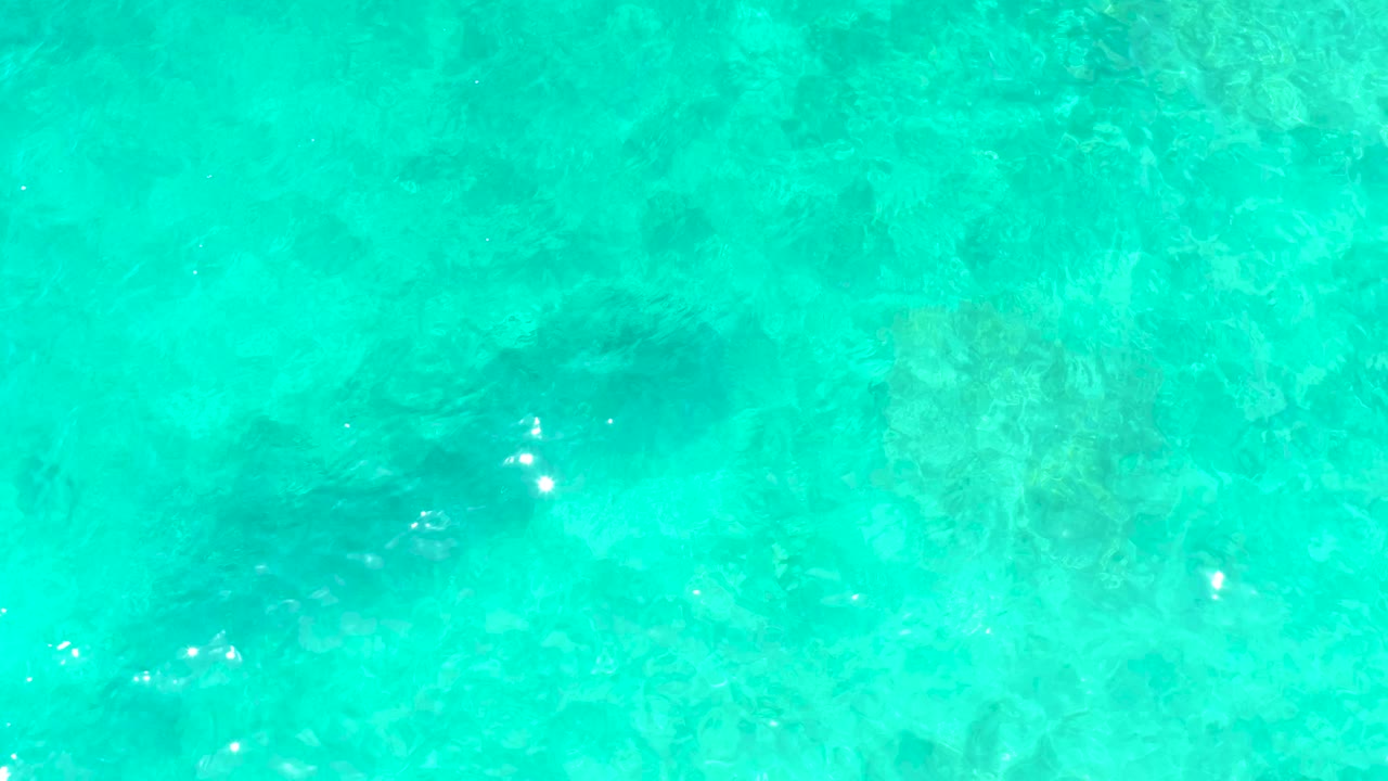 Clear aqua water with small bright surface reflections.