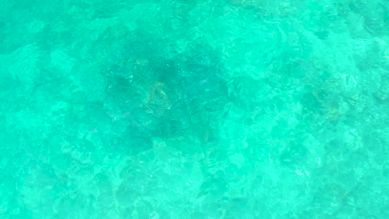 Turquoise shallow water with submerged rocks and ripples