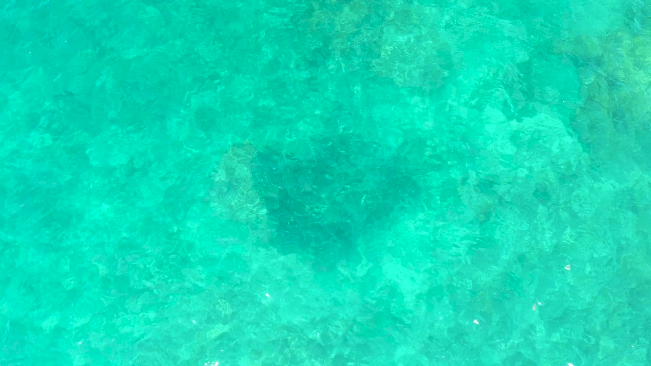 Turquoise shallow water with a faint sea turtle shape below the surface.