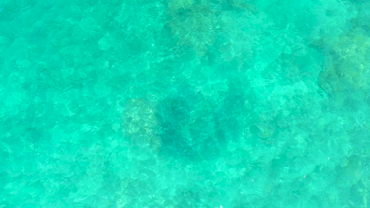 Clear water fills the frame above an uneven rocky seabed at El Tule Beach Los Cabos, with faint ripple bands and no visible people.