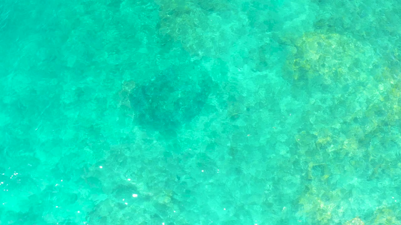 Clear turquoise water at El Tule Beach Los Cabos fills the frame, with underwater rocks softened by ripples and no visible people.