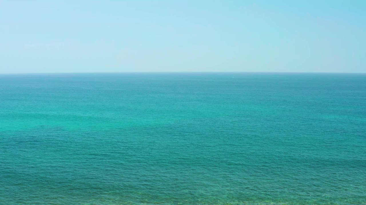 Blue-green ocean fills the frame at El Tule Beach Los Cabos, with faint surface texture, a clear sky band, and no visible people.