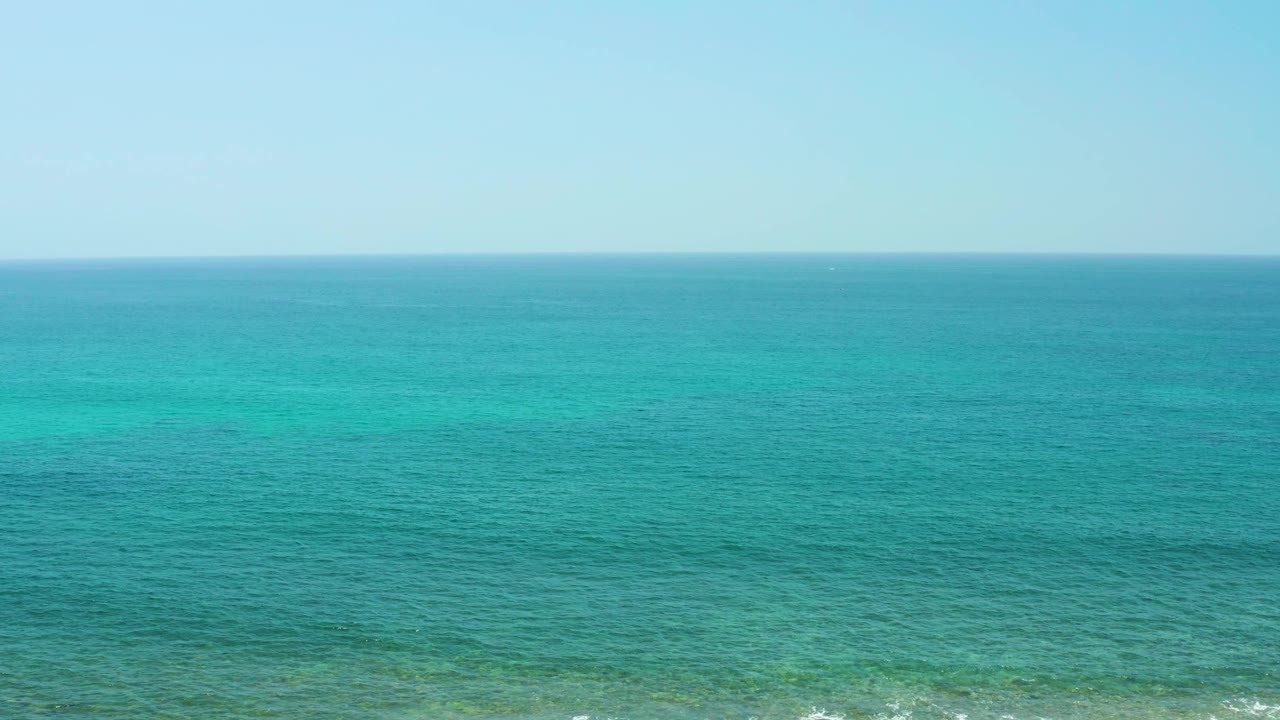 Calm ocean with faint darker patches below the surface.