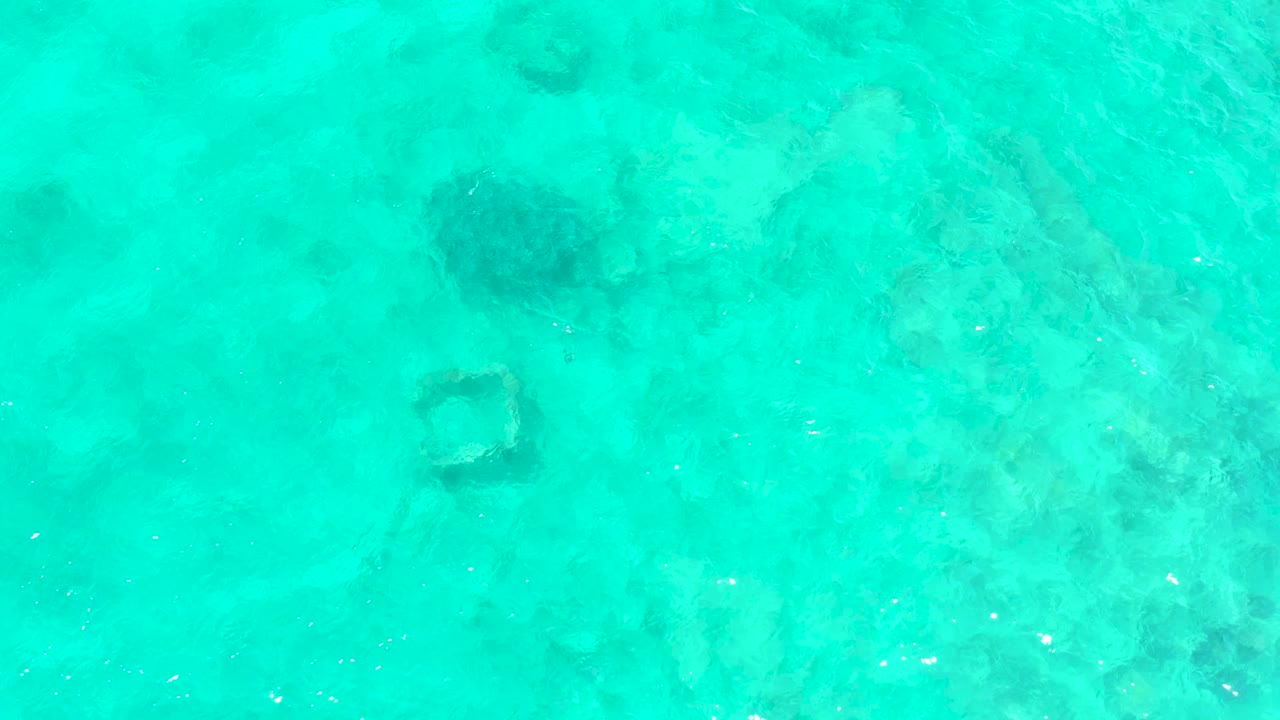 The square structure sits near the upper part of the frame in clear El Tule Beach water, with mottled seabed texture and no visible people.