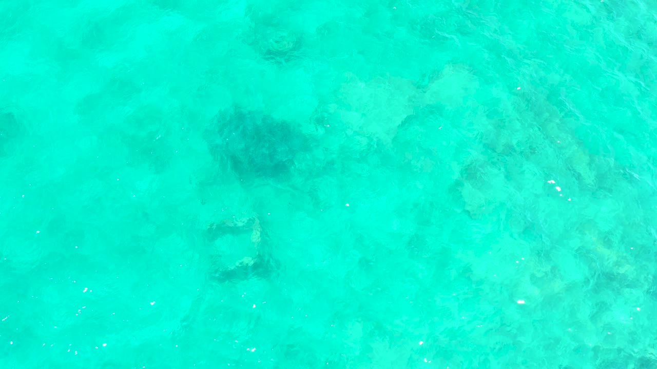The submerged square frame has shifted lower in the top-down view of El Tule Beach water, with pale sand tones, darker seabed patches, and no visible people.
