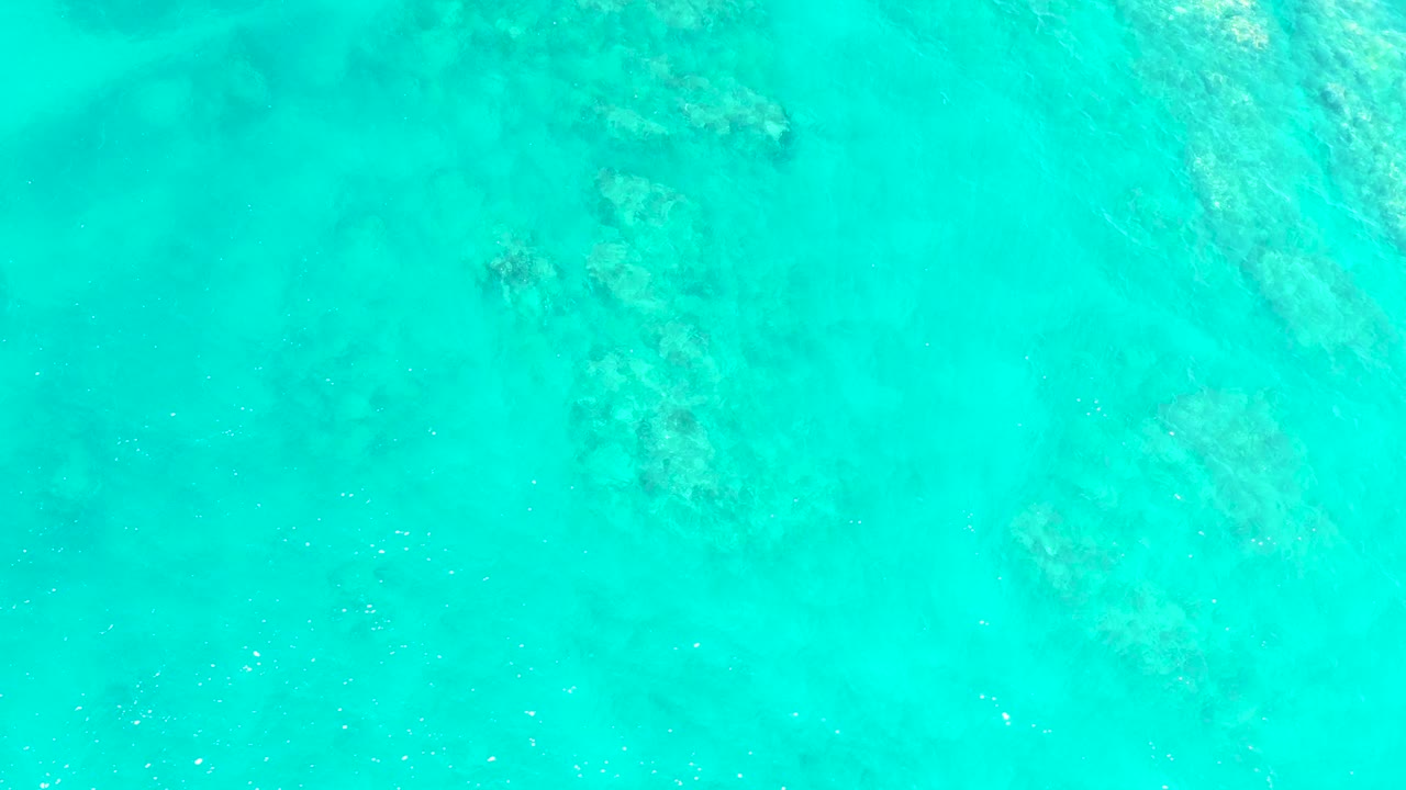 Transparent blue-green water over pale seabed and darker patches.