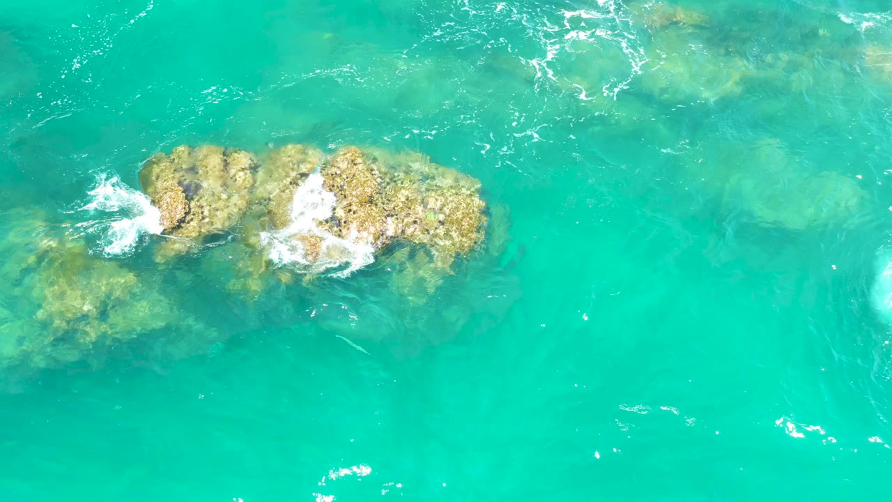 Turquoise water breaking over submerged rocks