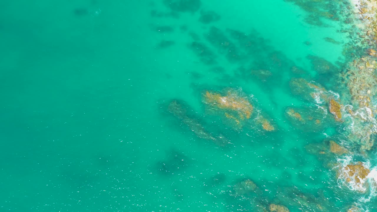 Turquoise shallows with rocky coast at right edge