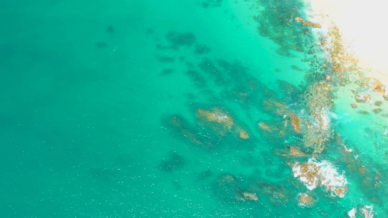 Aerial view of calm ocean water lapping over rocks