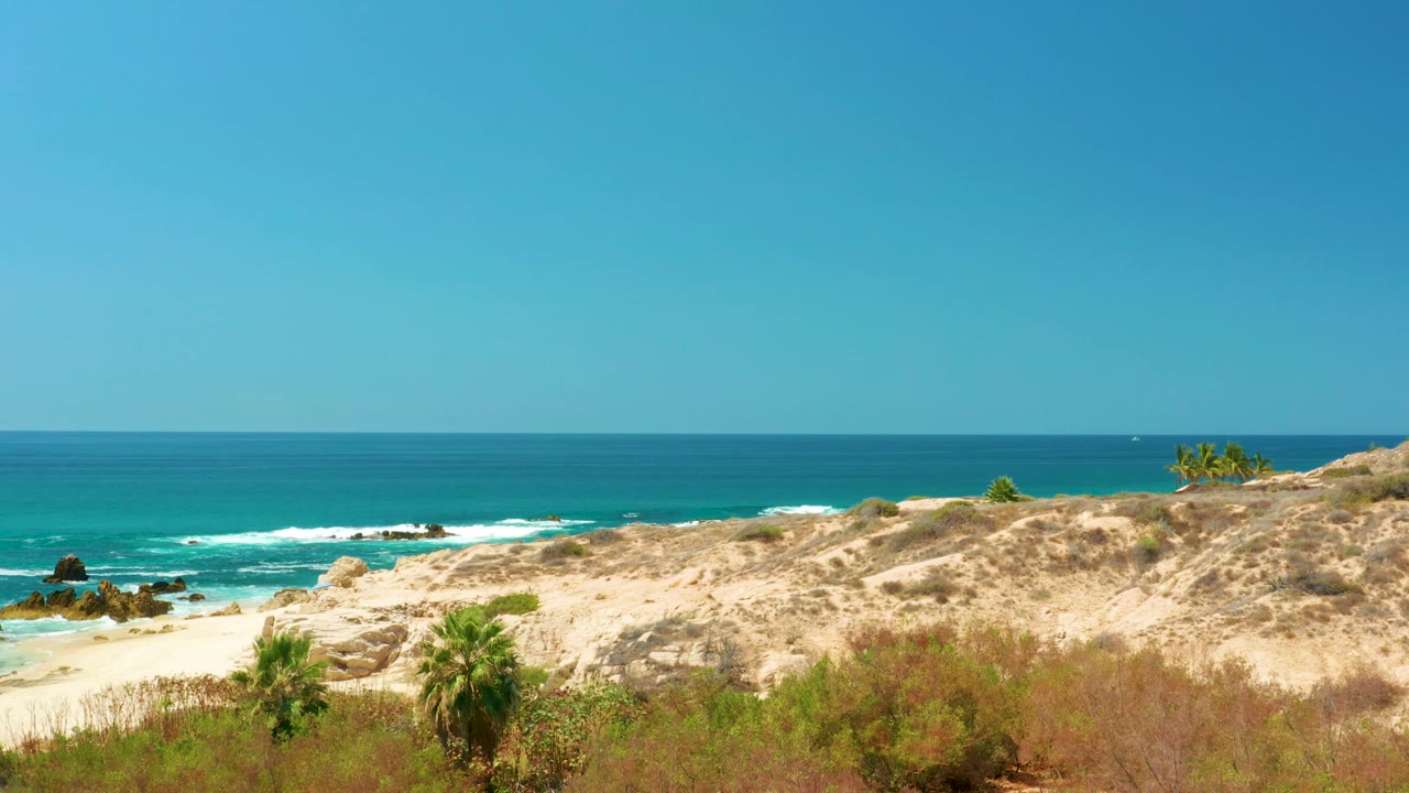 Wide coastal dune above turquoise ocean and rocky surf