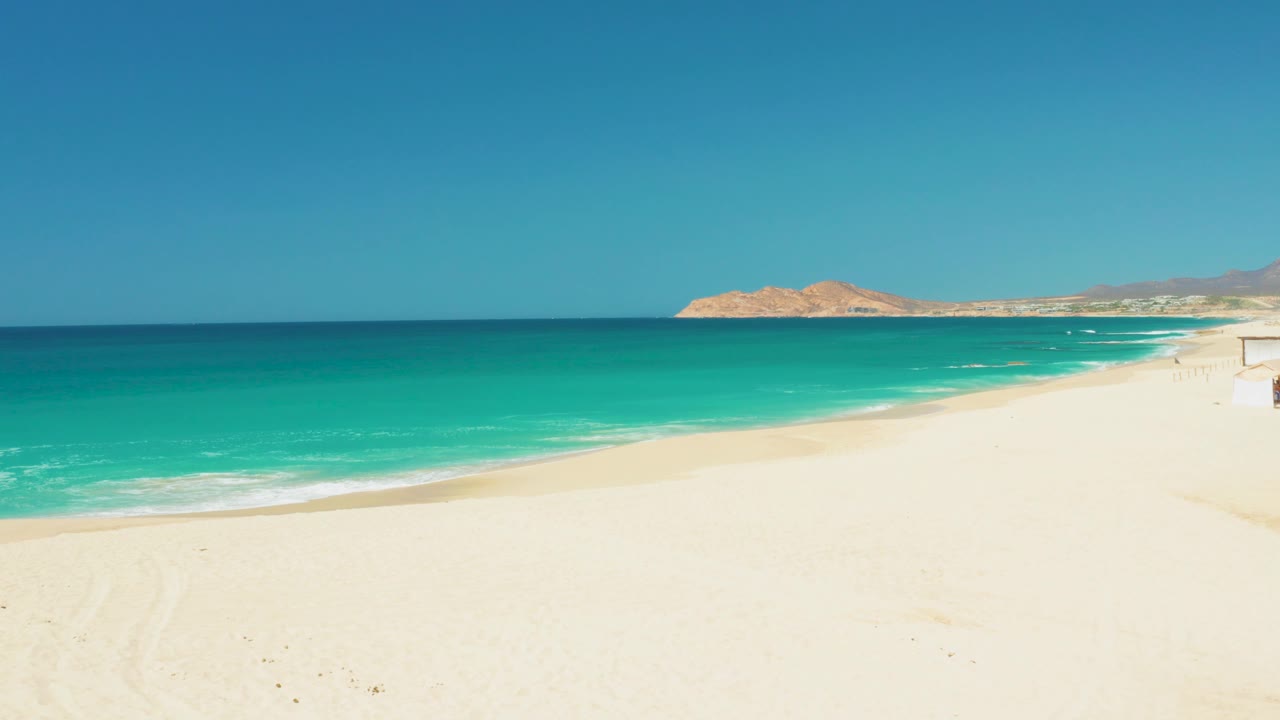 Open sandy shore with ocean waves and distant hills