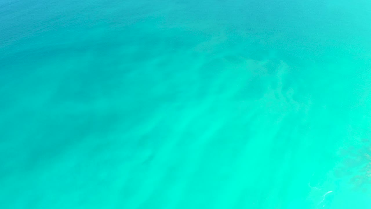 Clear turquoise water at Dreams Los Cabos shows a pale sandy bottom and soft surface ripples with no visible people.