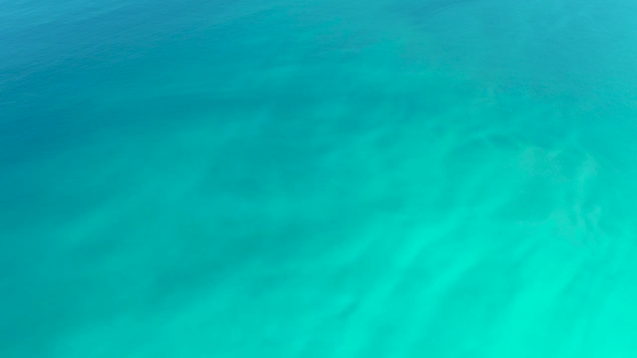 Clear turquoise seawater at Dreams Los Cabos fills the frame with faint darker patches under the surface and no visible people.