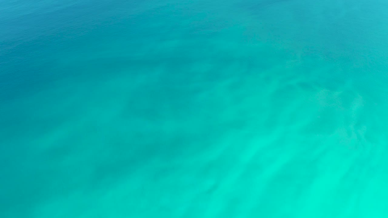 A blue green water surface at Dreams Los Cabos shows soft ripple lines and diffuse light movement with no visible people.