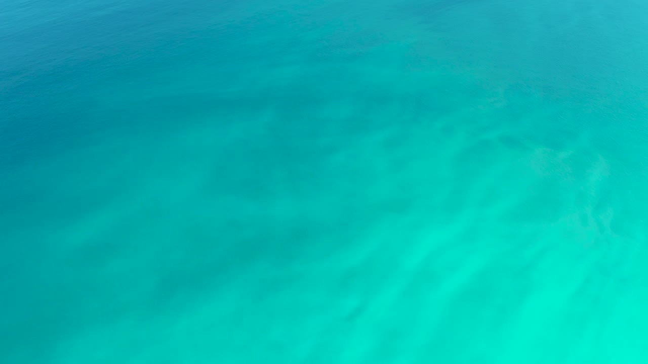 Clear turquoise sea at Dreams Los Cabos fills the view, with pale light patches spreading across the water and no visible people.