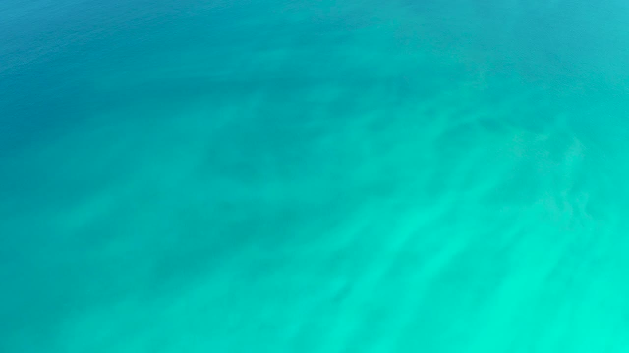 Turquoise underwater view with faint sand ripples.