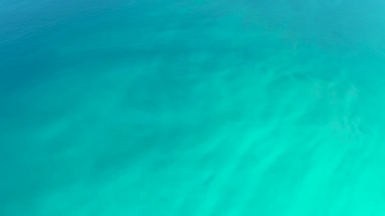Blue-green underwater view over pale rippled sand at Dreams Los Cabos, with the light pattern shifted slightly and no visible people.