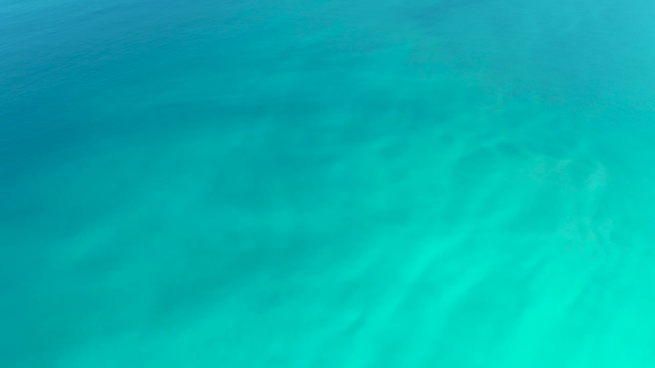Underwater view of sand ripples beneath calm turquoise water in Baja California Sur, with no visible people or objects breaking the frame.