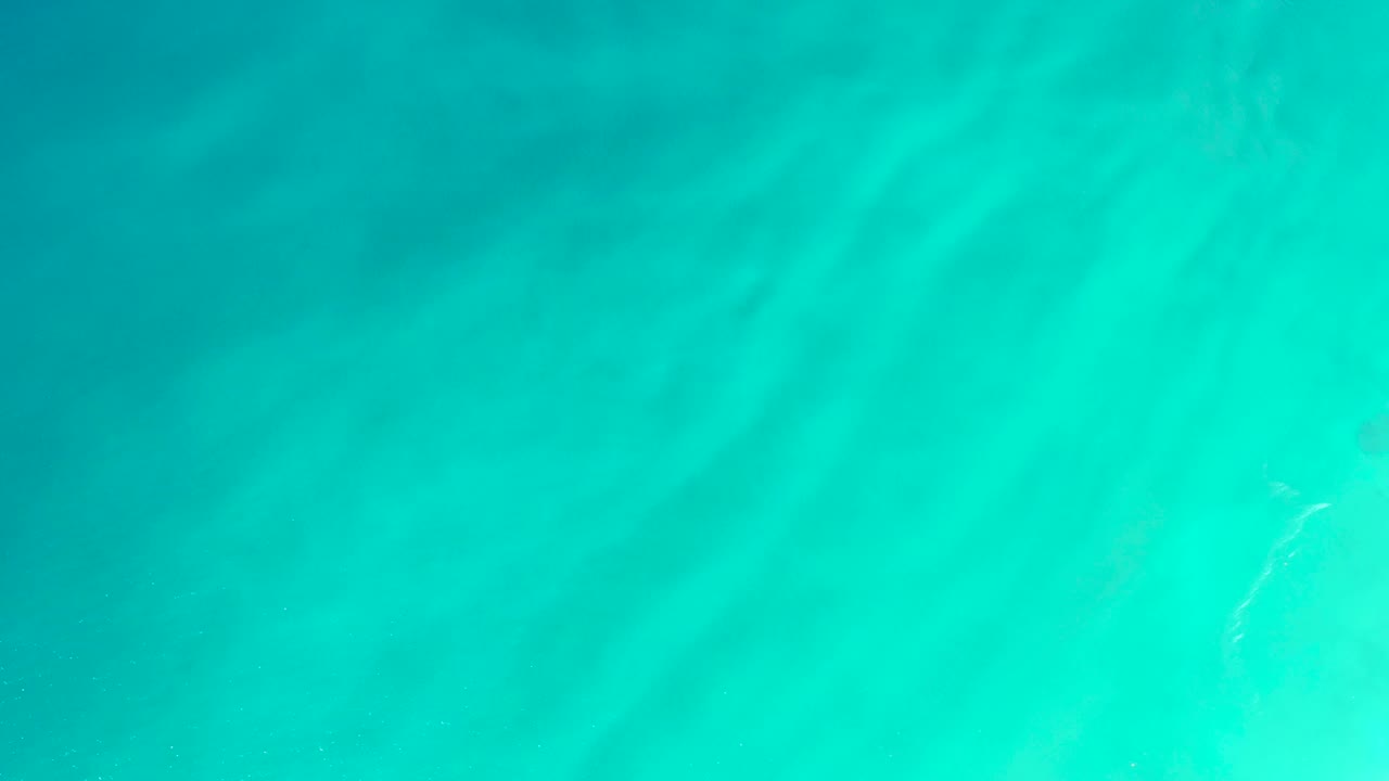 Clear turquoise ocean water at Dreams Los Cabos with a pale foam streak low in the frame and no visible people.