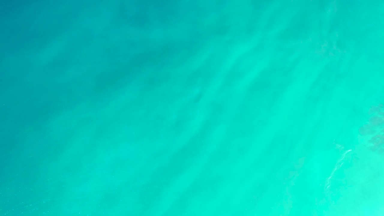 Clear aqua water fills the frame at Dreams Los Cabos, with diffuse sandy seabed markings and no visible people.