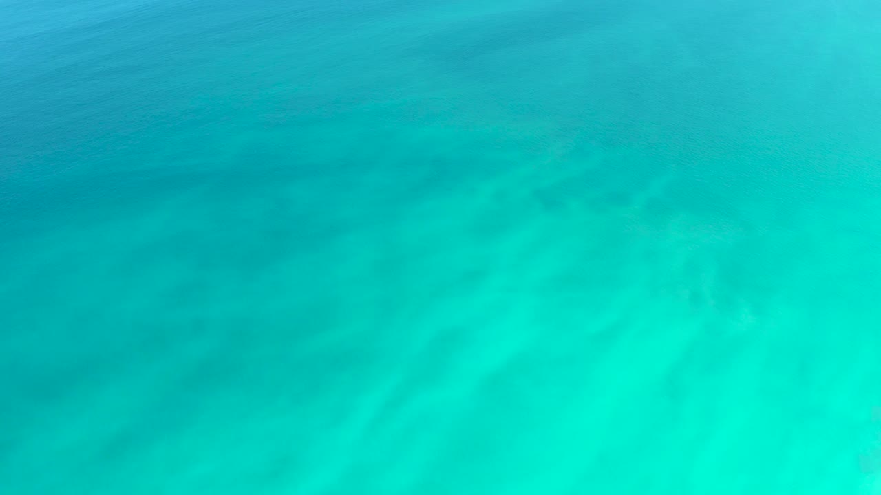 Blue-green water with soft ripples over sand