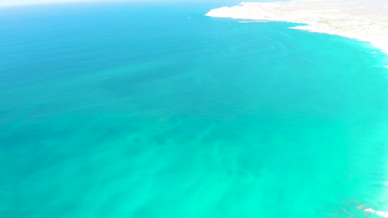 Turquoise coastal water with a bright sandy edge above.