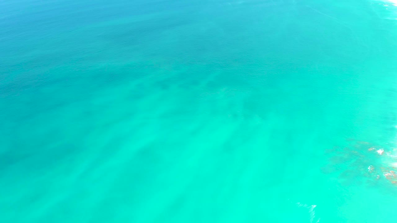 Clear turquoise water at Dreams Los Cabos fills the frame, with small sun glints near the right edge and no visible people.