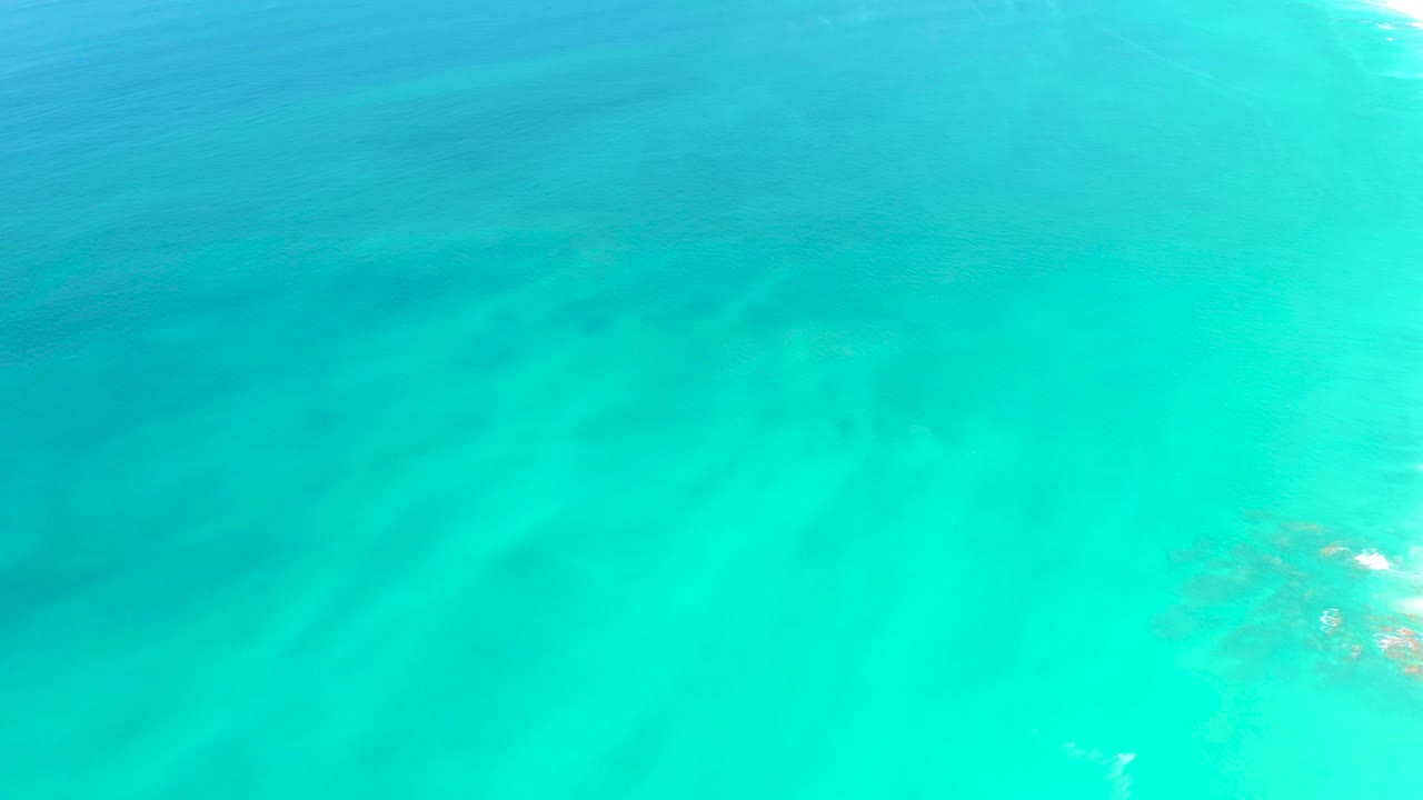Aerial-looking view of shallow turquoise water at Dreams Los Cabos shows pale seabed detail under a lightly rippled surface and no visible people.