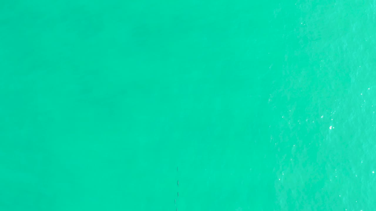 Top-down view of turquoise ocean at Los Frailes with a pale foamy patch developing on the right side and no visible people.