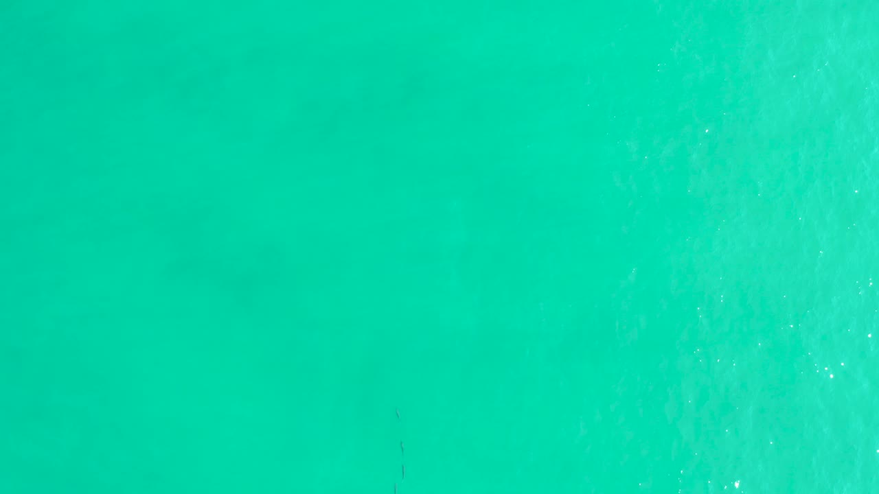 Overhead Los Frailes ocean water with brighter foam texture on the right half, calmer turquoise water to the left, and no visible people.