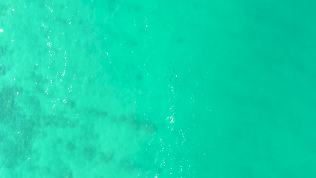 Overhead Los Frailes ocean frame with blue-green water, pale submerged texture across the center, and no visible people or vessels.