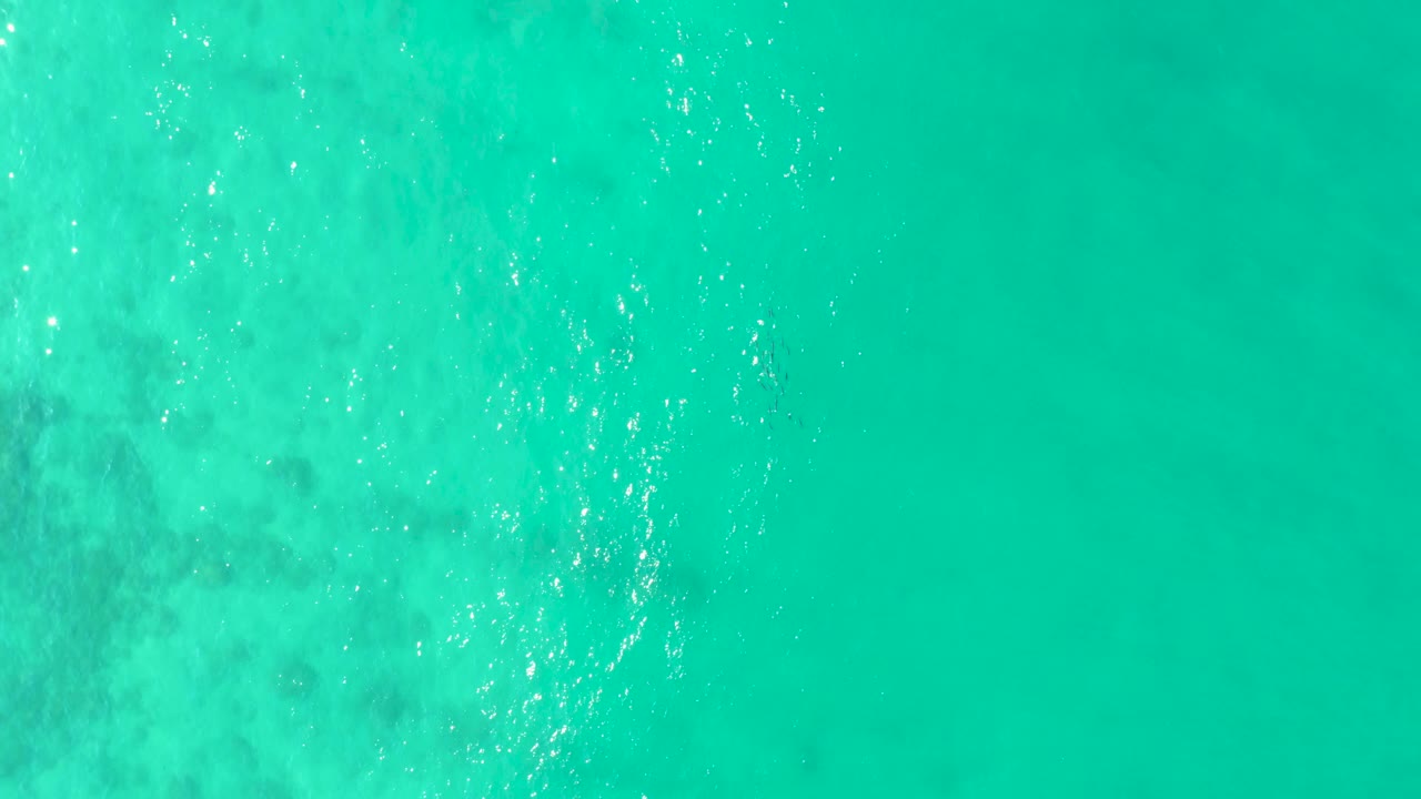 Straight-down Los Frailes water surface with calm turquoise color, diffuse pale patches under the surface, and no visible people, boats, or shore.