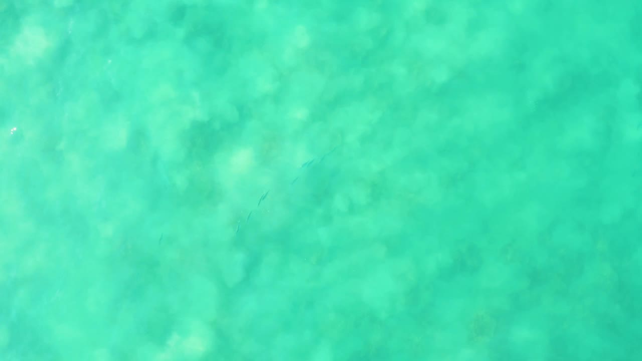 Clear green-blue ocean water at Los Frailes with pale underwater patches spread across the frame and no visible people.
