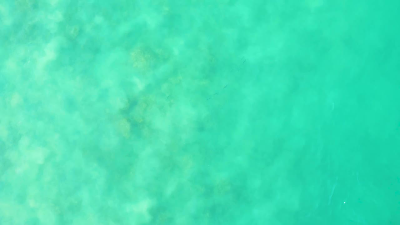 Aerial-style view of clear Los Frailes ocean water with soft underwater patches and faint ripples crossing the blue-green surface, no visible people.