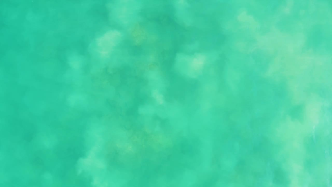 Aqua ocean water at Los Frailes seen from above, with diffuse lighter patches spread across the frame and no visible people.