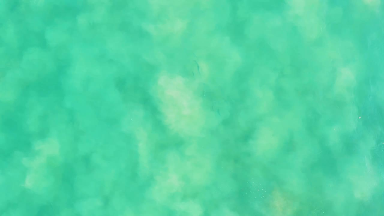 Clear green-blue ocean water fills the frame at Los Frailes, with soft ripple shadows drifting over the sandy bottom and no visible people.